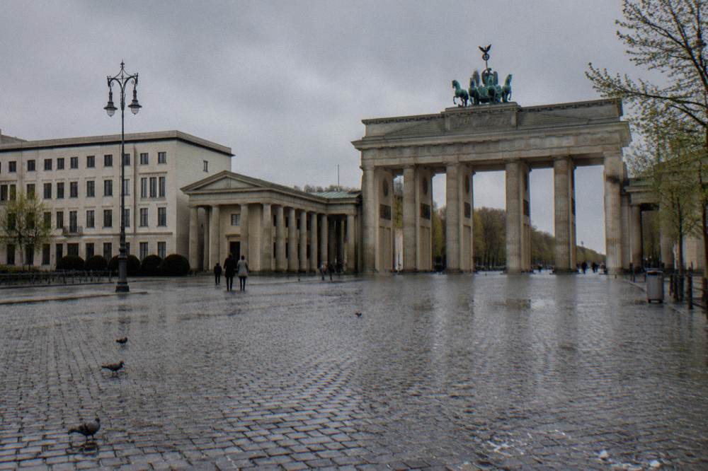 Group of walkers standing around a guide in a wide city square beside historic buildings