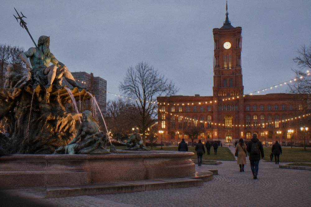 Illuminated public square in central Berlin at night with a historic landmark in view
