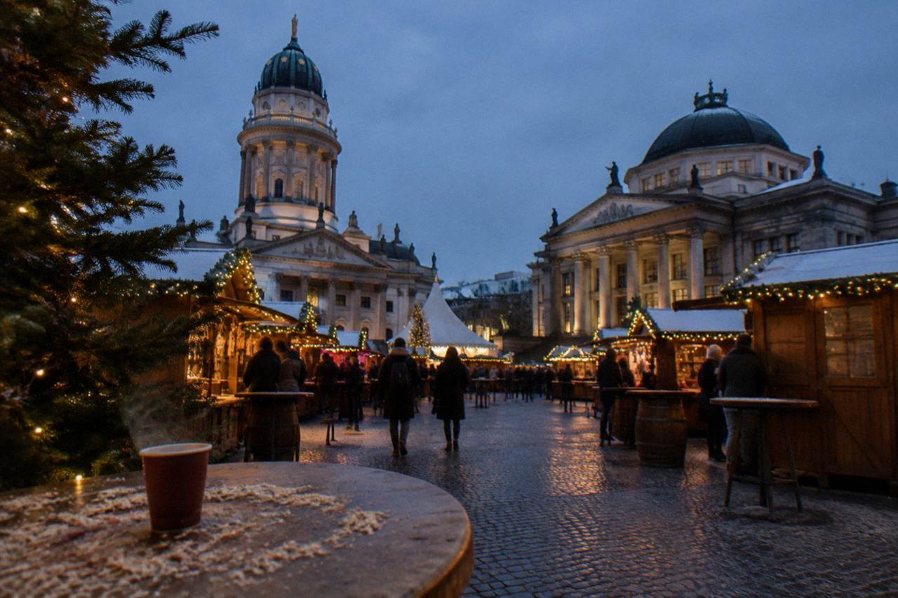 Wooden market stalls with string lights standing in a Berlin square at dusk