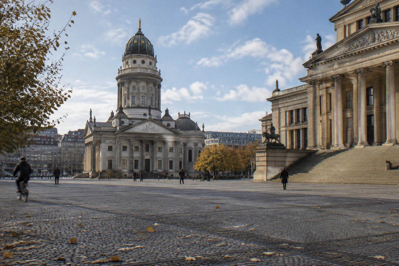A wide Berlin square with historic buildings under a clear sky