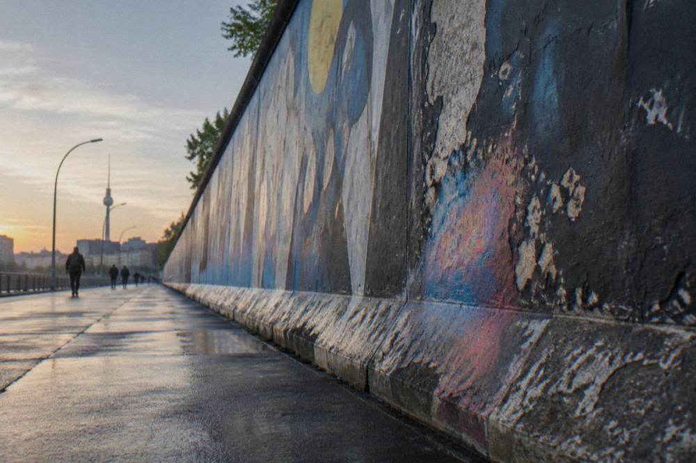 Painted section of the Berlin Wall stretching along a street in daylight