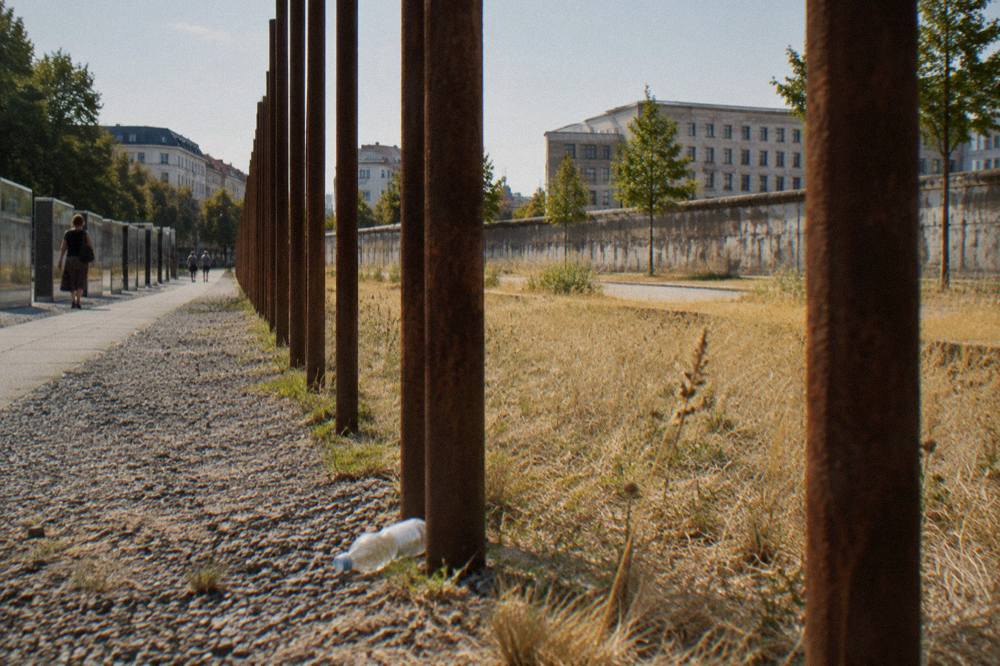 Open-air exhibition panels along Bernauer Strasse with a grassy strip and old wall segments in the foreground