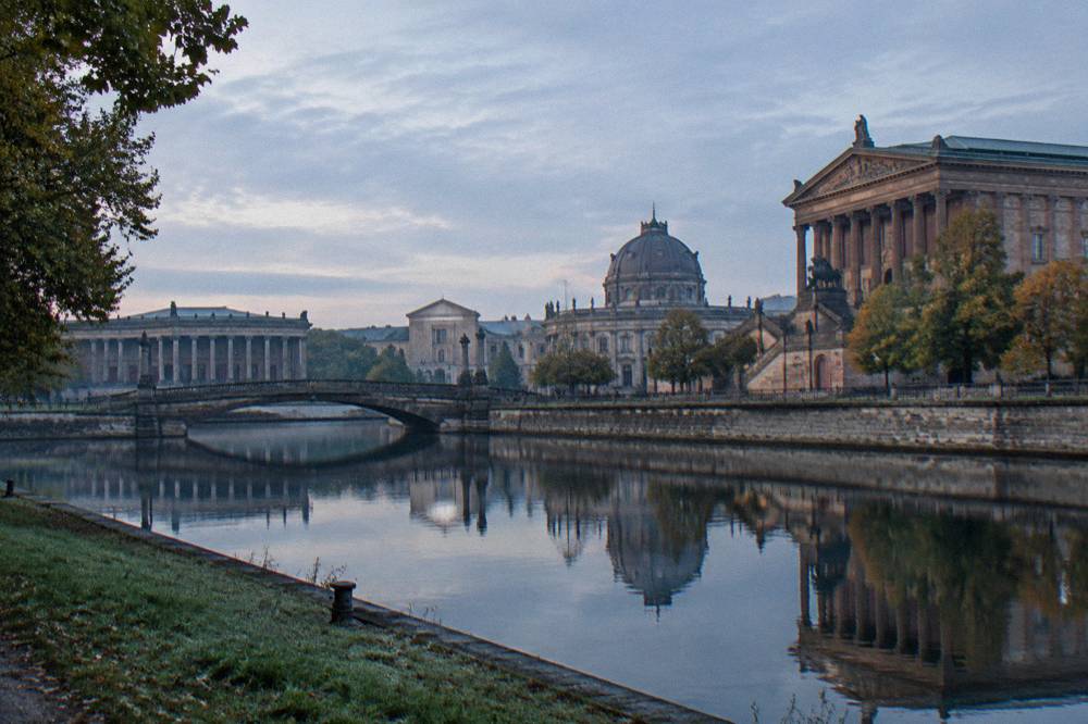 Museum Island buildings along the Spree with a stone bridge and domed architecture in daylight