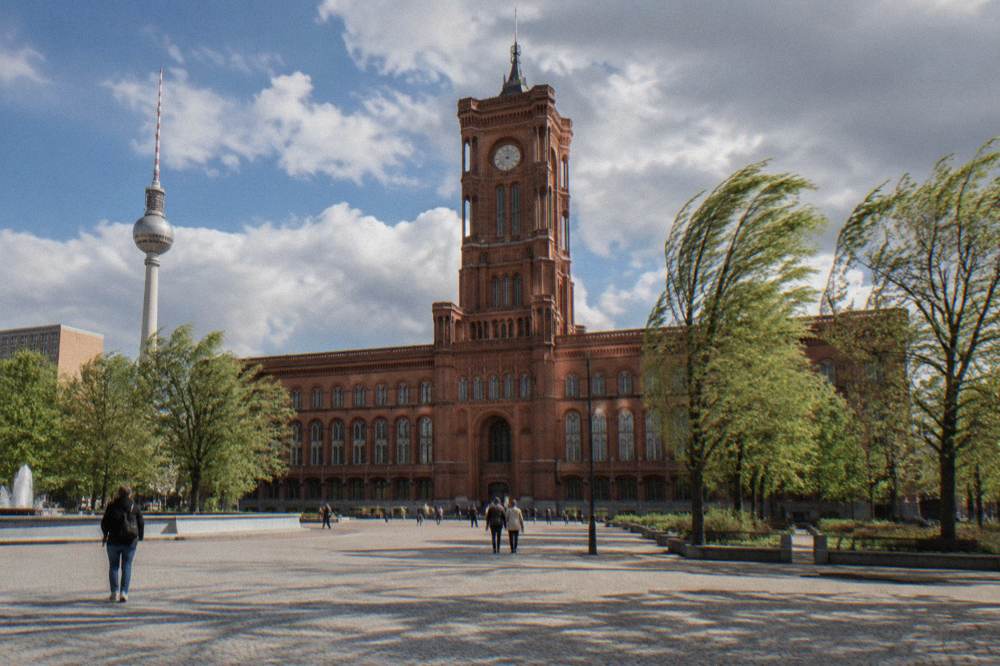 Red-brick town hall facade with a tower rising above a city square in central Berlin