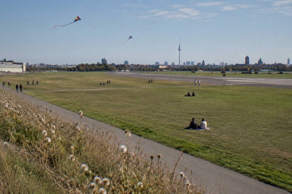 Open grass field with wide paths and distant city skyline under a clear sky
