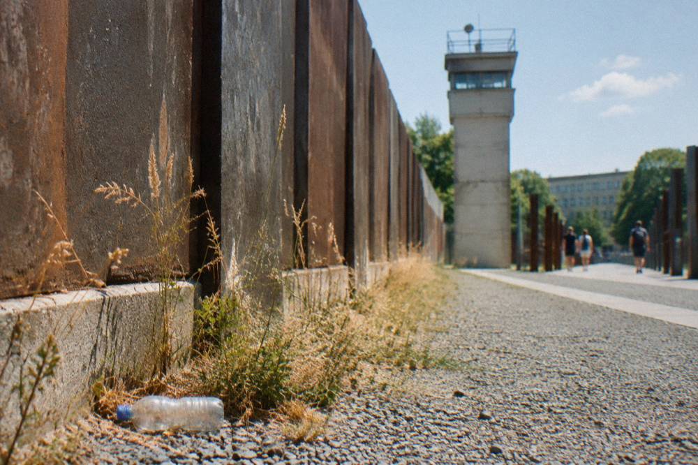 Steel wall slabs and a watchtower standing in the preserved border strip at the Berlin Wall Memorial
