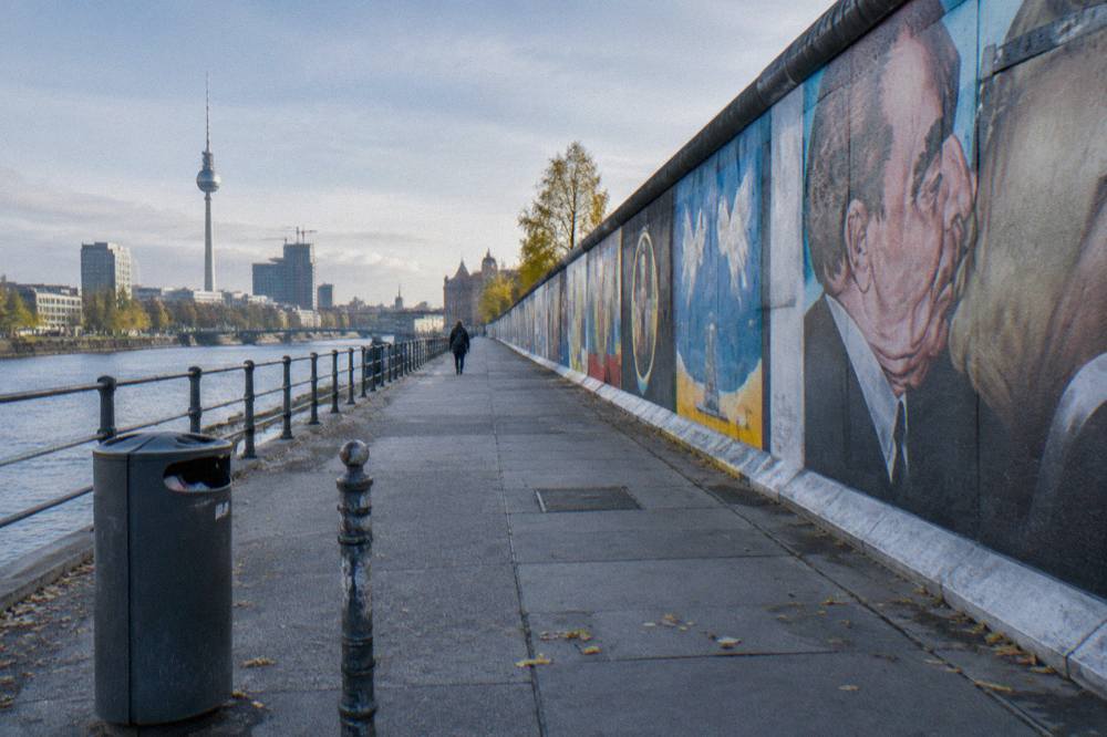Painted concrete wall panels of the East Side Gallery stretching down a Berlin street