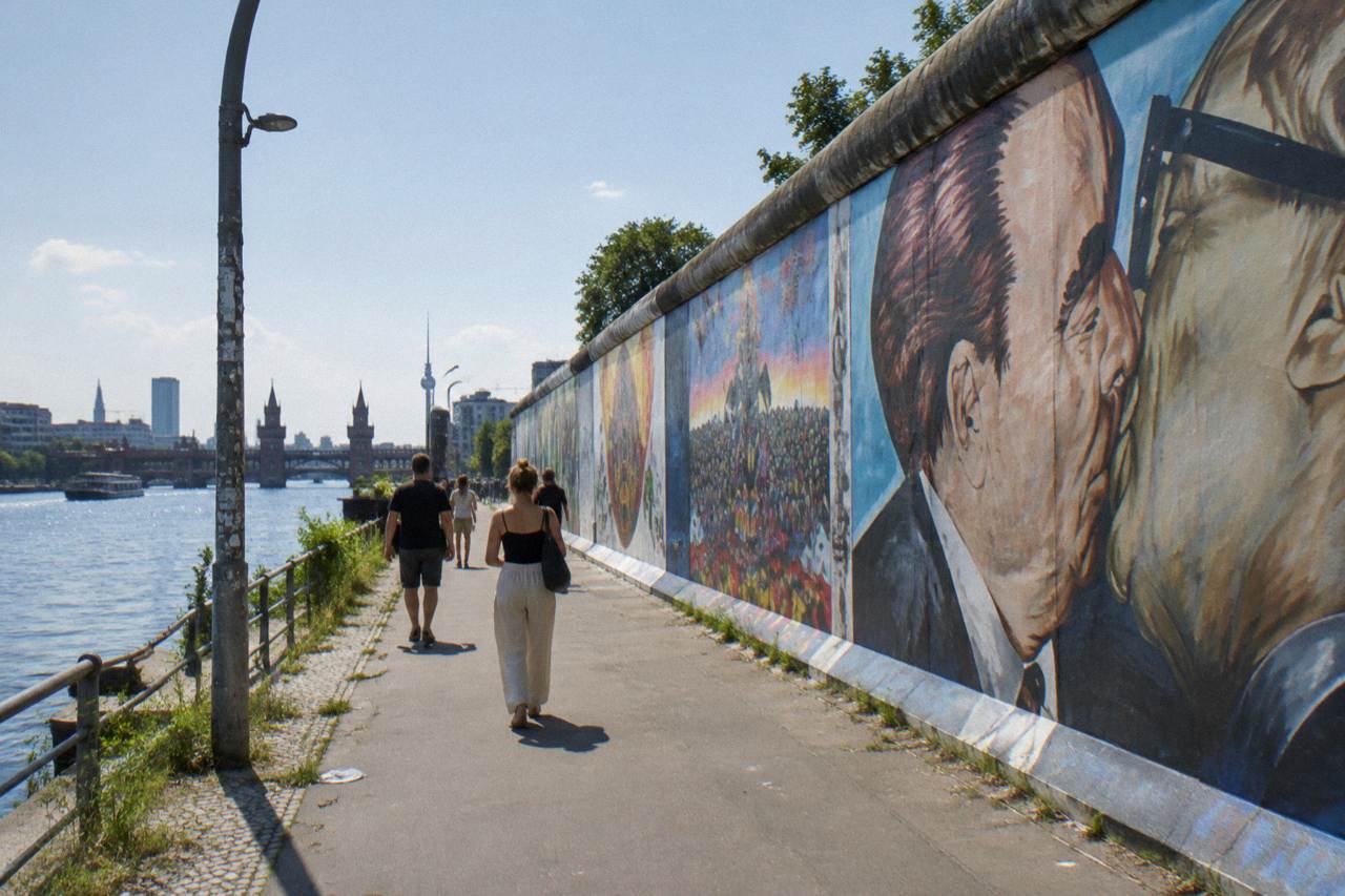 Painted wall sections of the East Side Gallery standing along a Berlin street under an open sky