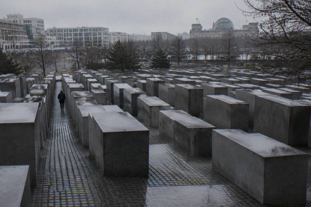 Grey concrete stelae of the Berlin Holocaust memorial standing in neat rows on an overcast day
