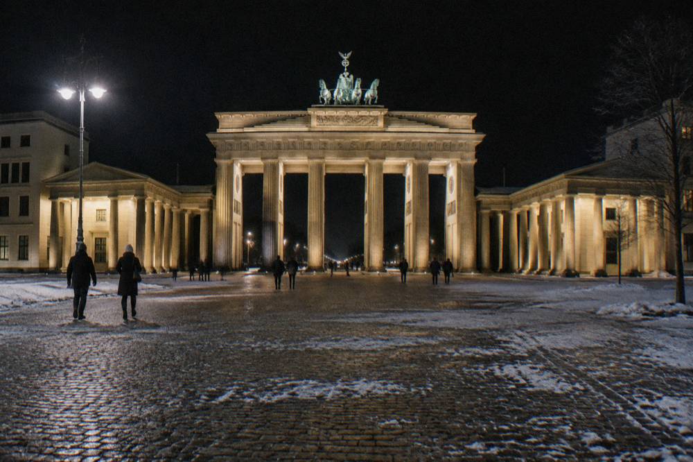 The Brandenburg Gate lit against a dark sky with an empty Pariser Platz