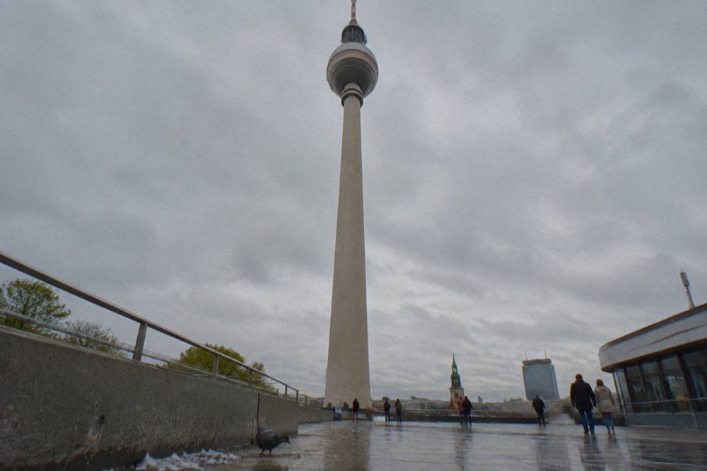 Steel tower shaft rising from a plaza with the sphere and observation deck visible against clouds