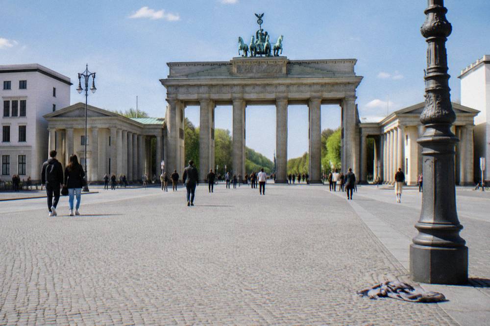 The open paving of Pariser Platz with the Brandenburg Gate framing the view toward the trees of the Tiergarten