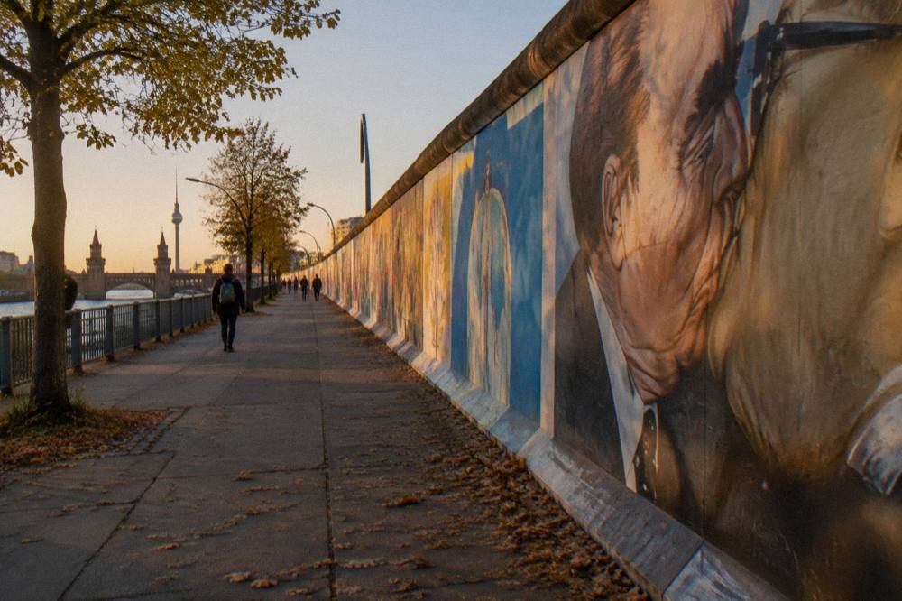 Long row of painted wall panels of the East Side Gallery seen from the wide sidewalk on Mühlenstraße