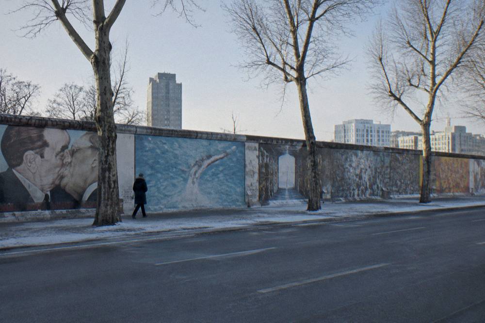 Painted wall panels of the East Side Gallery with the street and open sky behind them