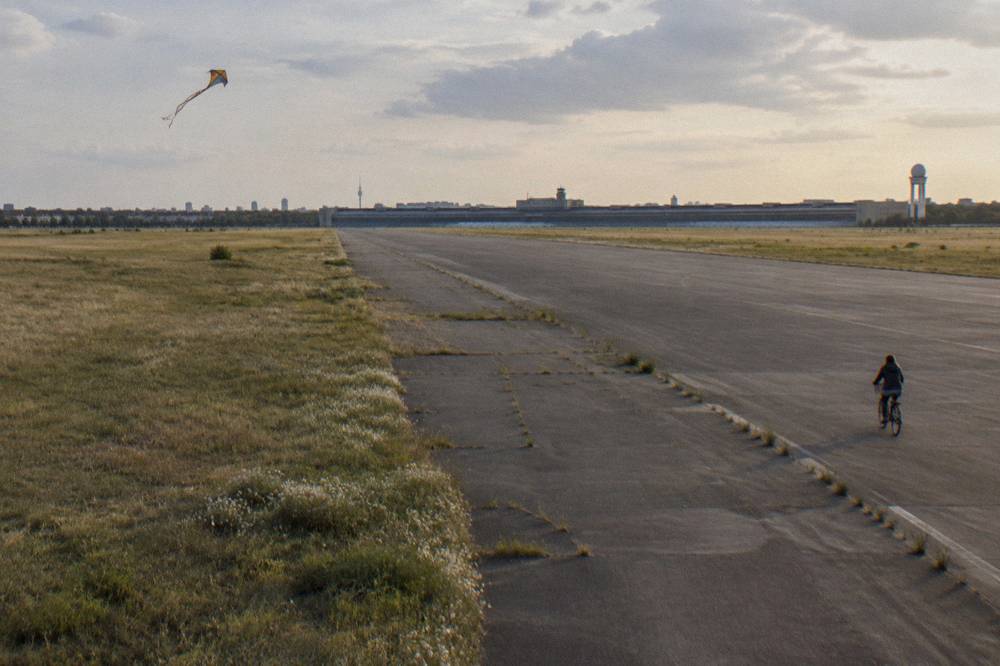 Wide open grass field with a runway edge under a wide sky