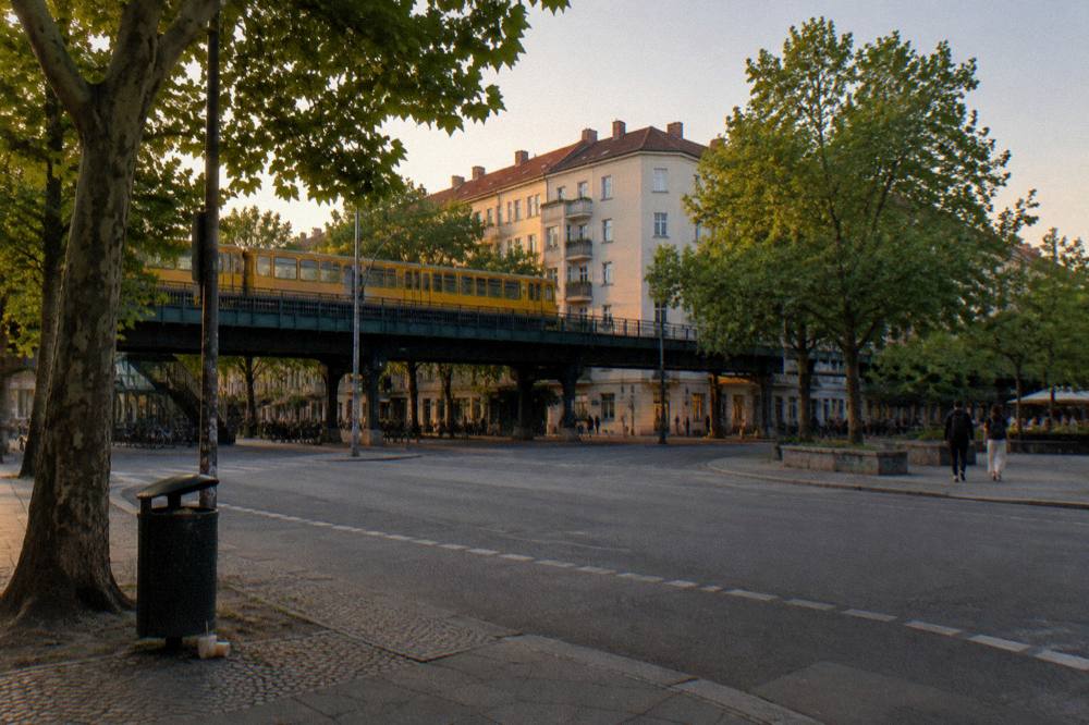City street corner with a U-Bahn sign and old apartment buildings under a bright sky
