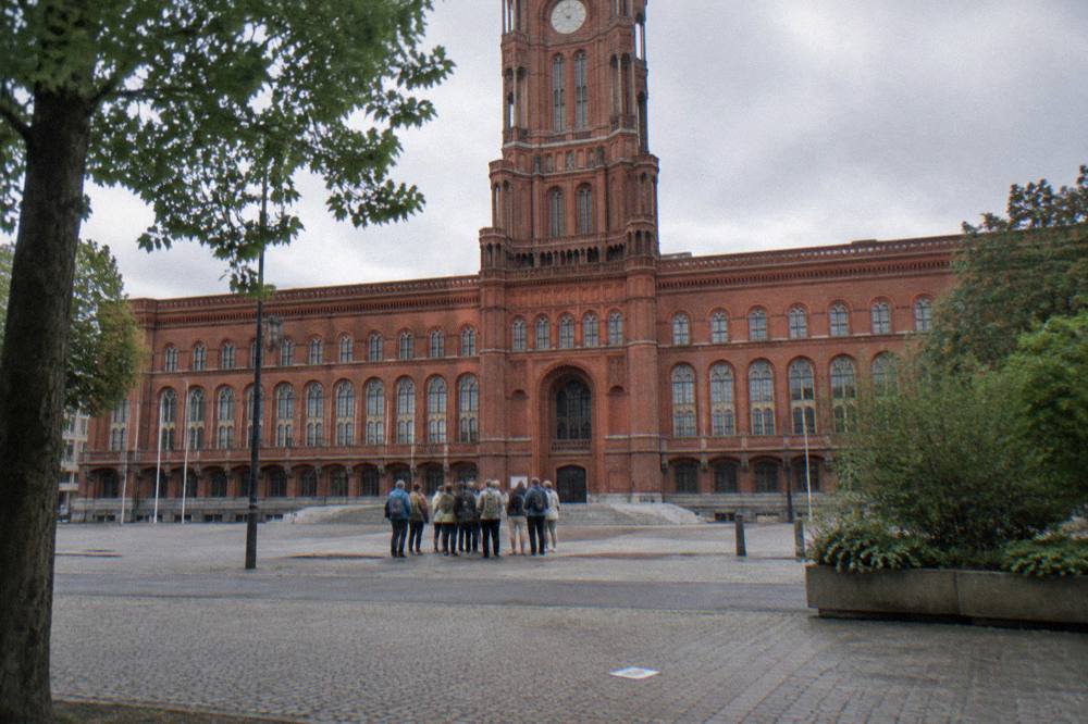 Red brick town hall facade with a group gathering at the steps outside